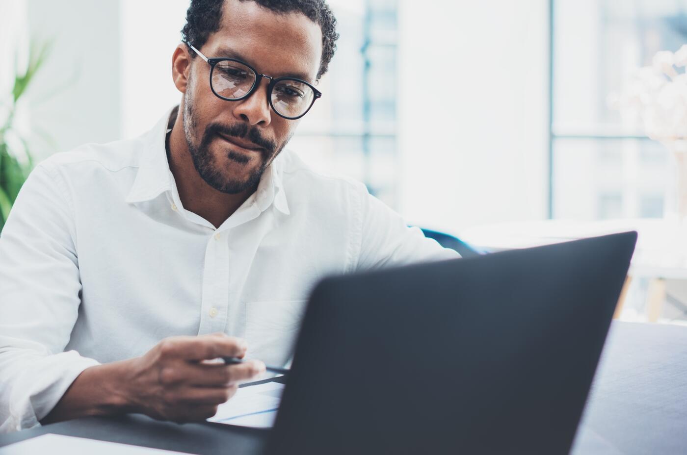 Businessman wearing glasses and using laptop in work office