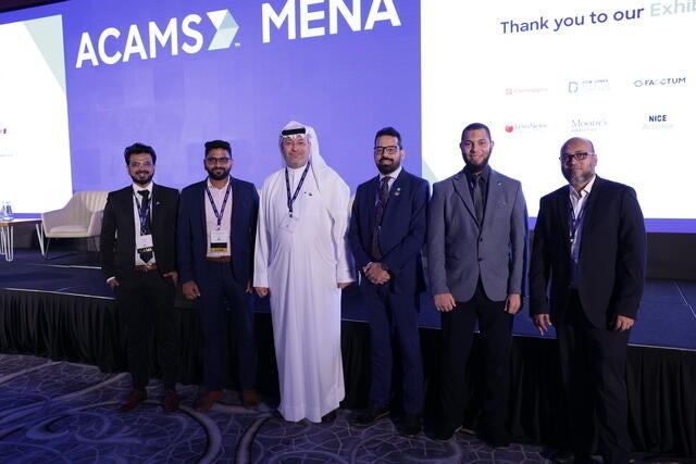 MENA Conference Recap Photo - Six attendees posing by the stage