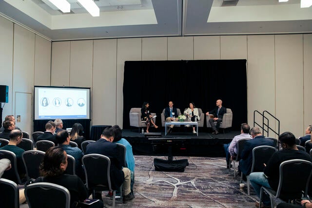 FinTech Conference Recap Photo - Wide view of four panel speakers and audience
