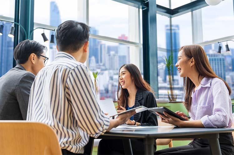 Team of 4 collaborating and smiling at table