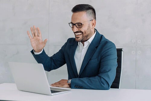 Businessman waving hello to laptop screen