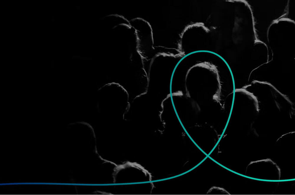 A crowd of people gathered in a dimly lit room, illuminated by a prominent blue circle in the center.